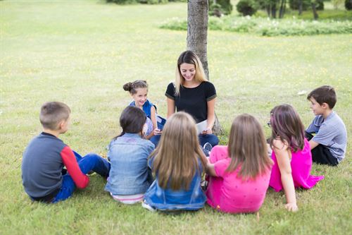 Teacher reading to students outside in the park